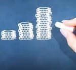 Hand drawing ascending bar graph on chalkboard, symbolizing growth and progress.